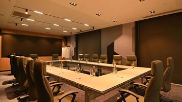 A conference room with a long table, multiple chairs, and a whiteboard.