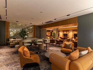A modern hotel lobby with a marble wall, seating area, and a bar. - Mercure Tashkent North (Tashkent)