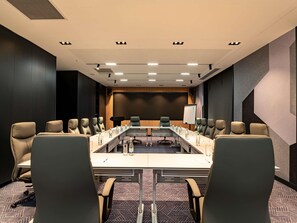 A conference room with a long table, multiple chairs, a whiteboard, and a projector screen. - Mercure Tashkent North (Tashkent)