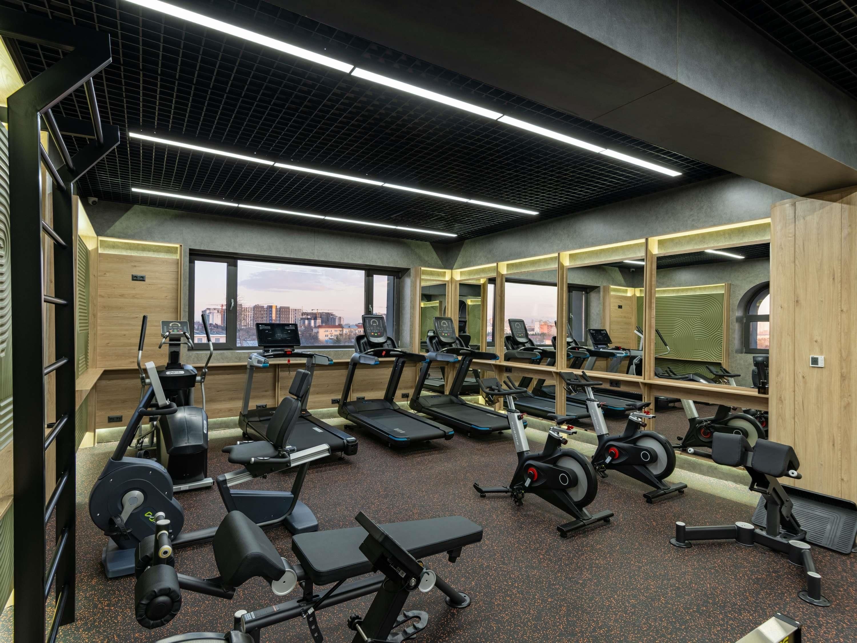 Un gimnasio con cintas de correr, bicicletas estáticas y máquinas de pesas.