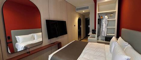 A hotel room with a bed, a TV, a mirror, and a wardrobe.
