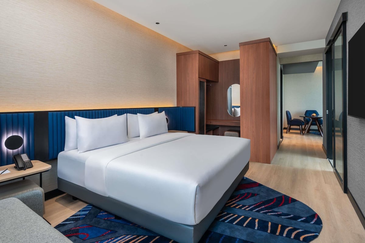 Una habitación de hotel con cama, mesita de noche y un escritorio con silla.