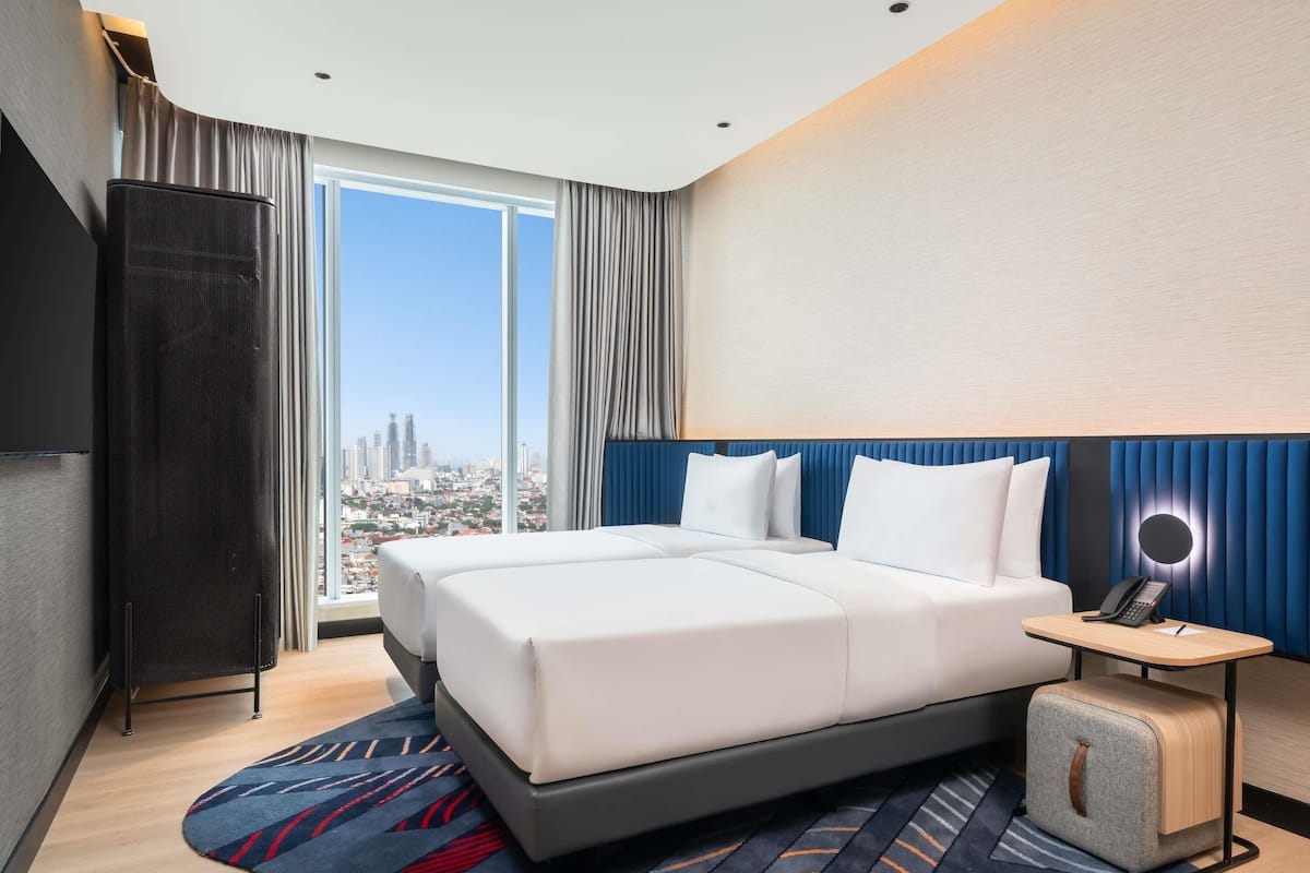 Una habitación de hotel moderna con una cama grande, un escritorio con teléfono y vistas a la ciudad.
