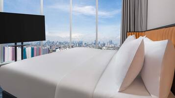 A hotel room with a large bed, a TV, and a city view.