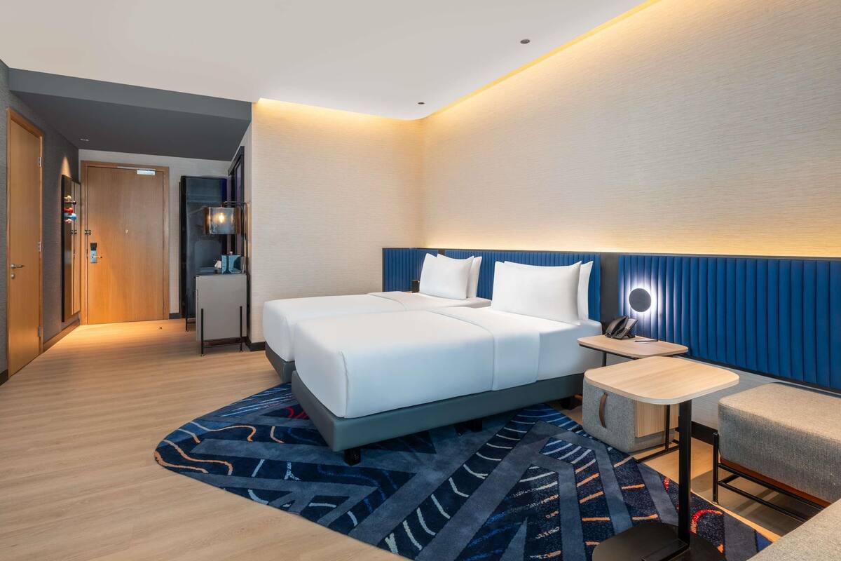 Una habitación de hotel moderna con una cama grande, una mesita de noche y un pequeño escritorio.
