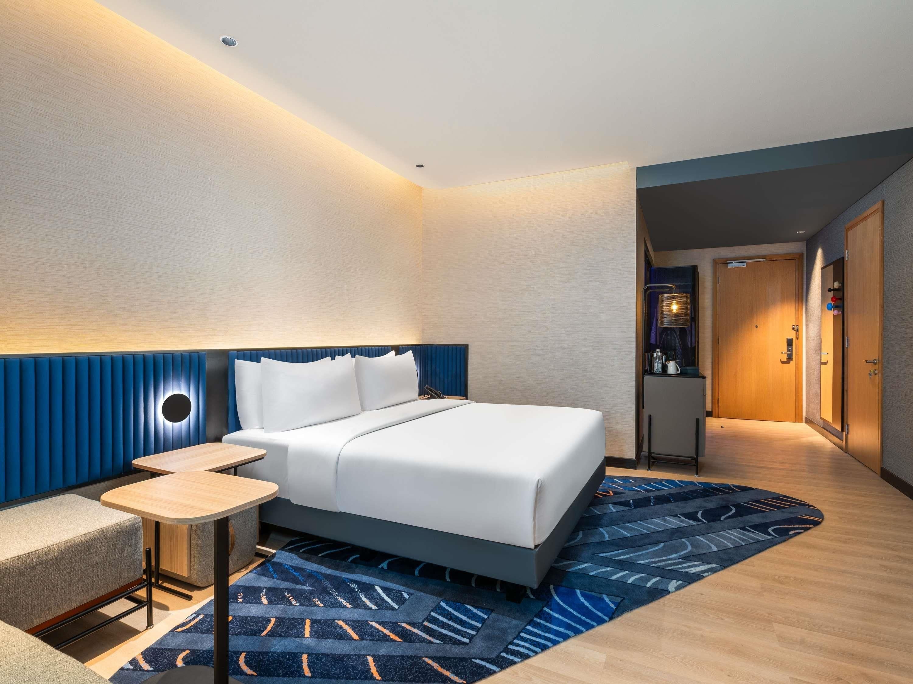 Une chambre d’hôtel moderne équipée d’un lit, d’une table de chevet et d’un petit coin salon.
