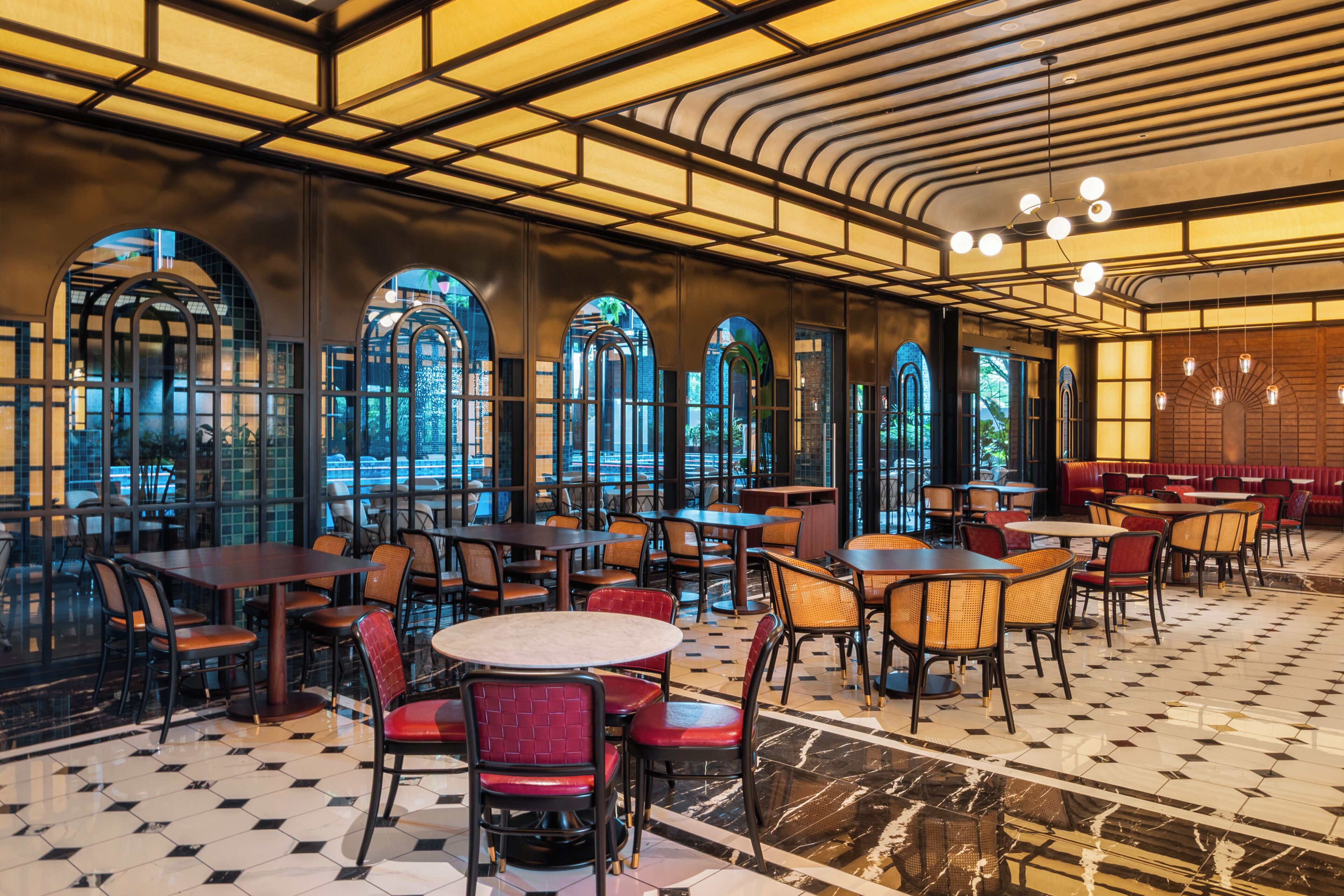 A restaurant with a checkered floor, tables, chairs, and arched windows.