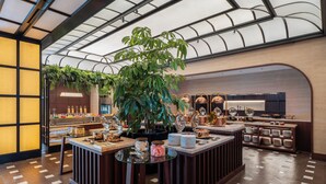 A modern kitchen with a central island, a large potted plant, and various kitchenware. - Novotel Tangerang Bsd City (Pagedangan)