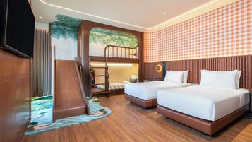 A hotel room with a bunk bed, two single beds, a flat-screen TV, a wall mural, and a checkered wall pattern.