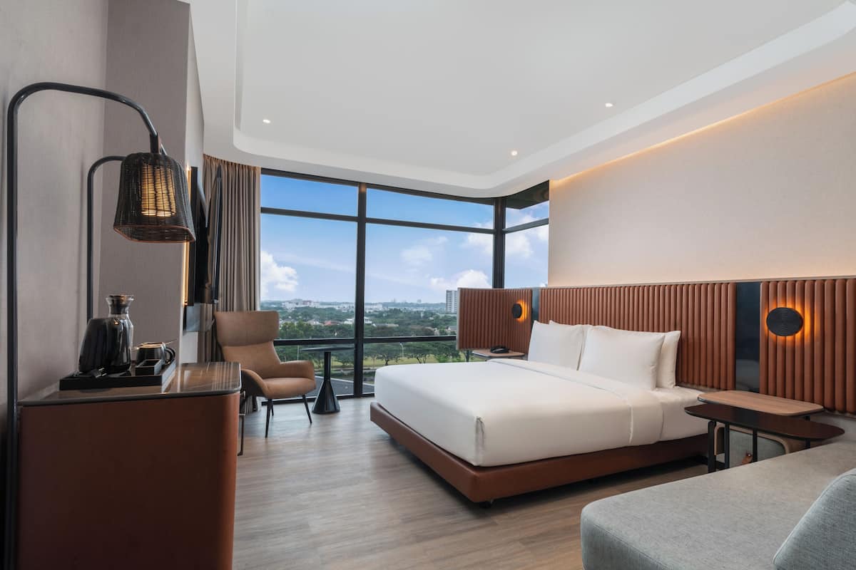 Habitación de hotel moderna con una cama grande, un escritorio, una silla y vistas a la ciudad.