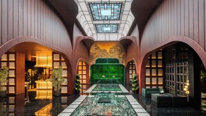 A spacious lobby with a central seating area, a high ceiling with skylights, and a marble floor. - Novotel Tangerang Bsd City (Pagedangan)