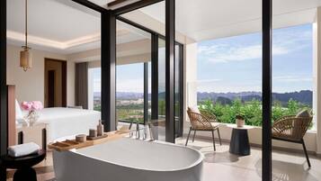 A modern bathroom with a freestanding bathtub, a large window, and a view of the landscape.