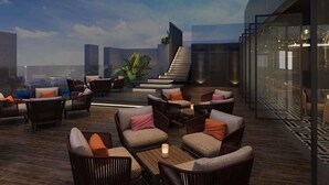 A rooftop lounge with wicker furniture, a staircase, and a city view. - Pullman Ninh Binh (Ninh Binh)
