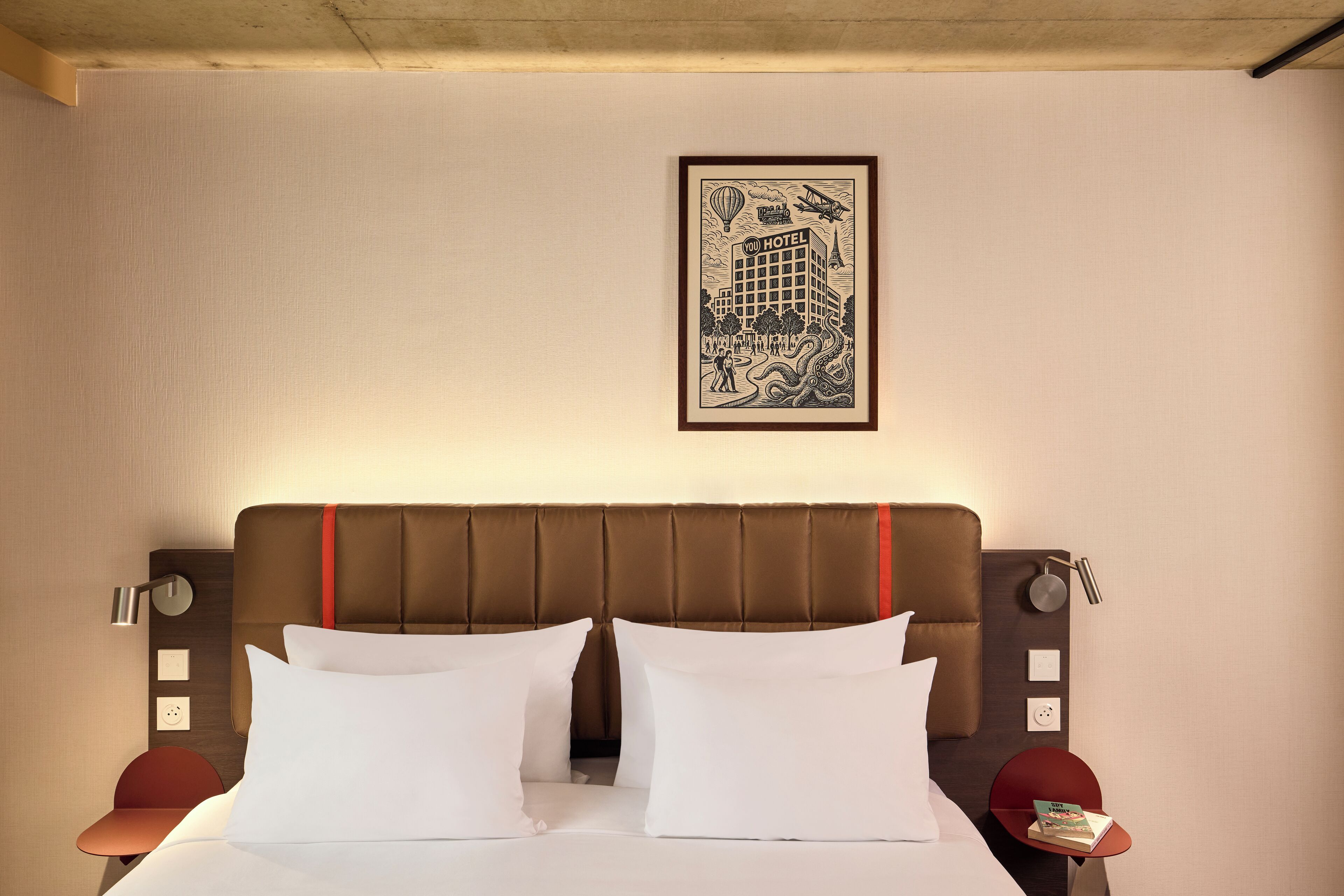 A hotel room with a large bed, a headboard with a red accent, two bedside tables, and a framed picture on the wall.