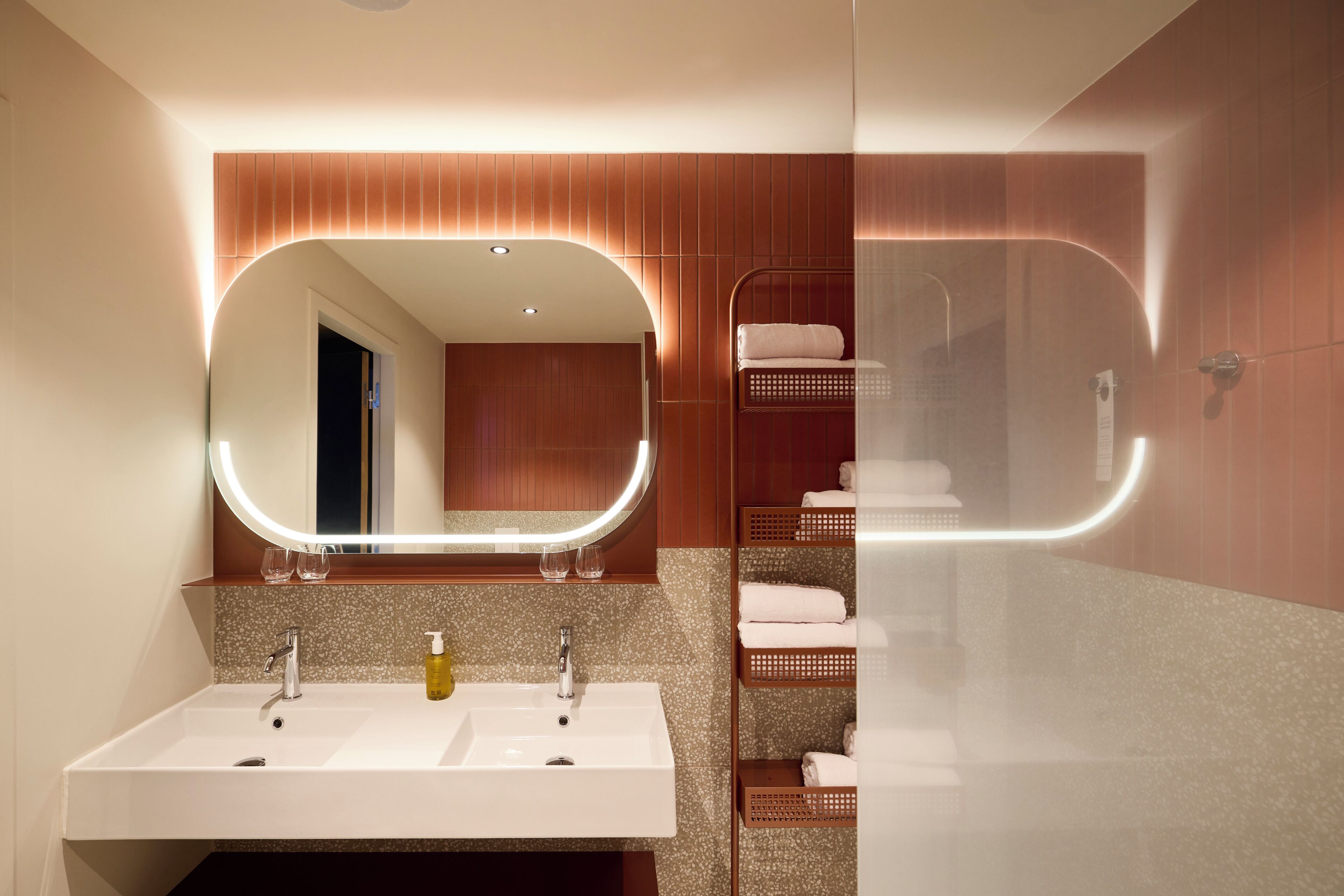 A modern bathroom with a large mirror, two sinks, and a glass shower enclosure.