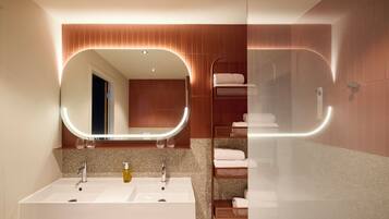 Een moderne badkamer met een grote spiegel, twee wasbakken en een douchecabine met glazen wanden.