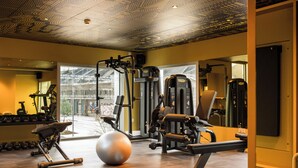 A modern gym with various exercise equipment, a large exercise ball, and a view of the outside through large windows. - You Hotel Amiens - Handwritten Collection (Amiens)