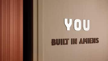 A sign with the text "YOU BUILT IN AMIENS" on a textured wall.