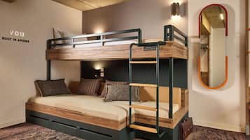A bunk bed room with a built-in desk, a mirror, and a carpeted floor.