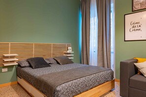 Ein Schlafzimmer mit einem Bettgestell aus Holz, einer grau gemusterten Bettdecke und einem Kopfteil mit horizontalen Lamellen.