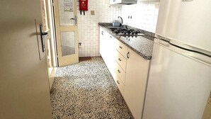 Una cucina con mobili bianchi, un piano di lavoro in granito e un piano cottura integrato.
