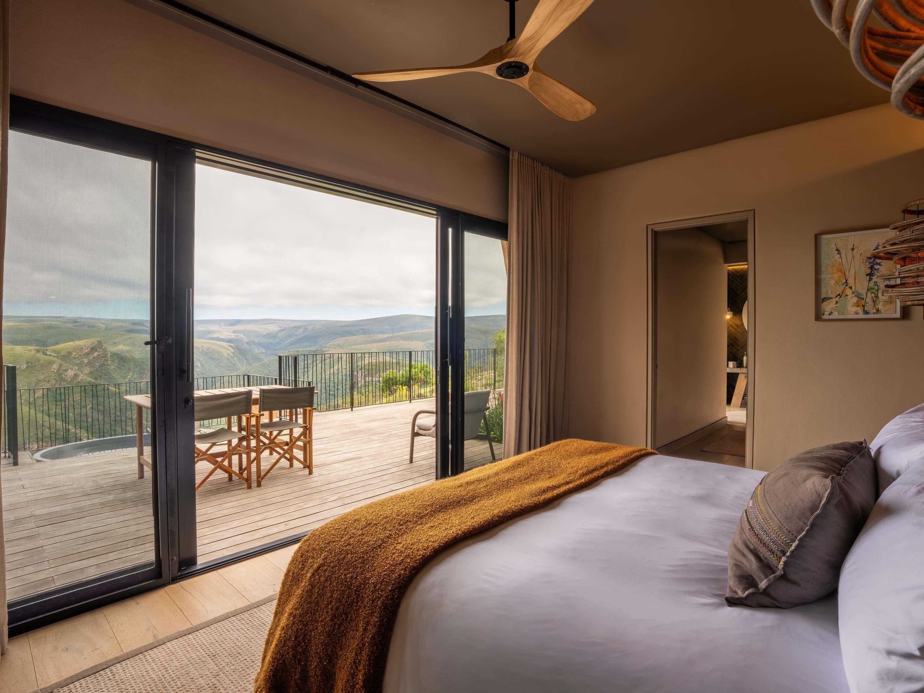 A bedroom with a large window, a ceiling fan, and a view of the countryside.