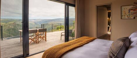 A bedroom with a large window, a ceiling fan, and a view of the countryside.