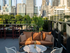 A rooftop terrace with a sofa, chairs, and a table, overlooking a cityscape with modern buildings. - Mercure Melbourne La Trobe Street (West Melbourne)