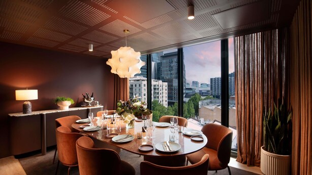 A modern dining room with a round table, orange chairs, a city view, and a ceiling with a geometric pattern. - Mercure Melbourne La Trobe Street (West Melbourne)