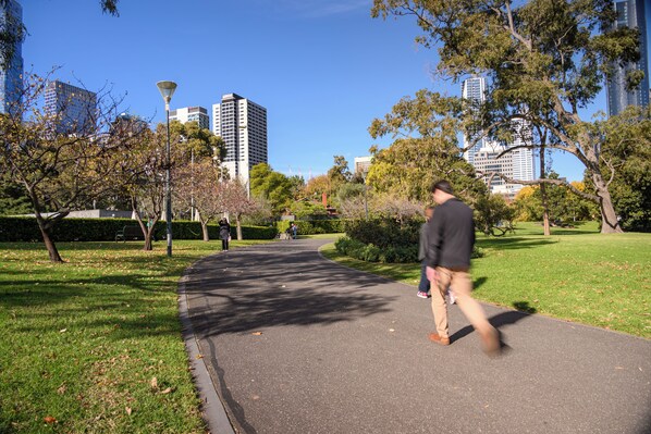 A park with a paved path, trees, and a distant cityscape. - Mercure Melbourne La Trobe Street (West Melbourne)