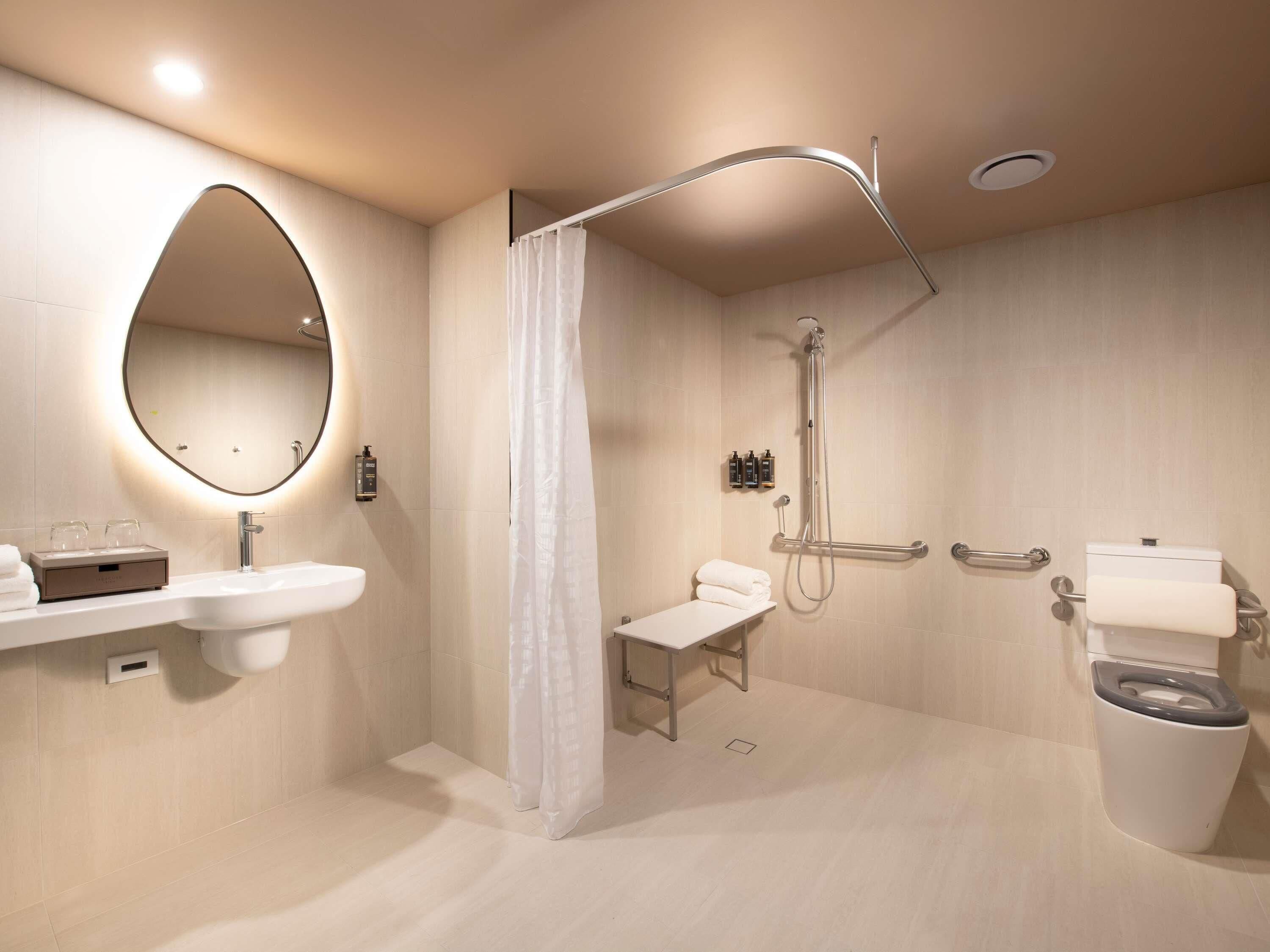 Een moderne badkamer met een wastafel, douche, toilet en handdoekrek.