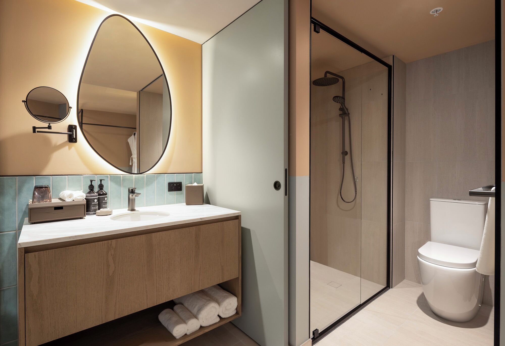A modern bathroom with a large mirror, a sink, and a shower.