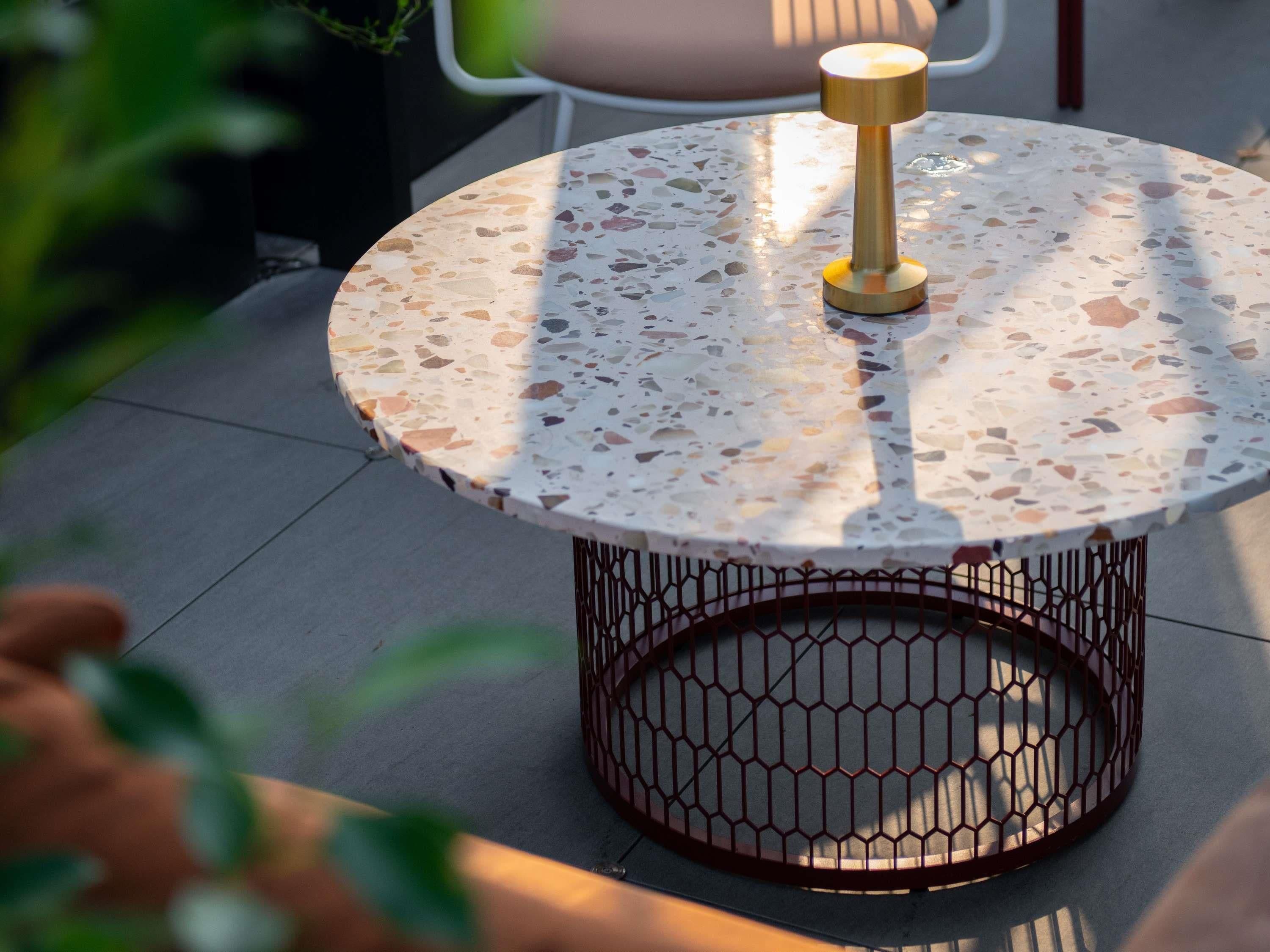 A round table with a terrazzo top and a metal wireframe base.