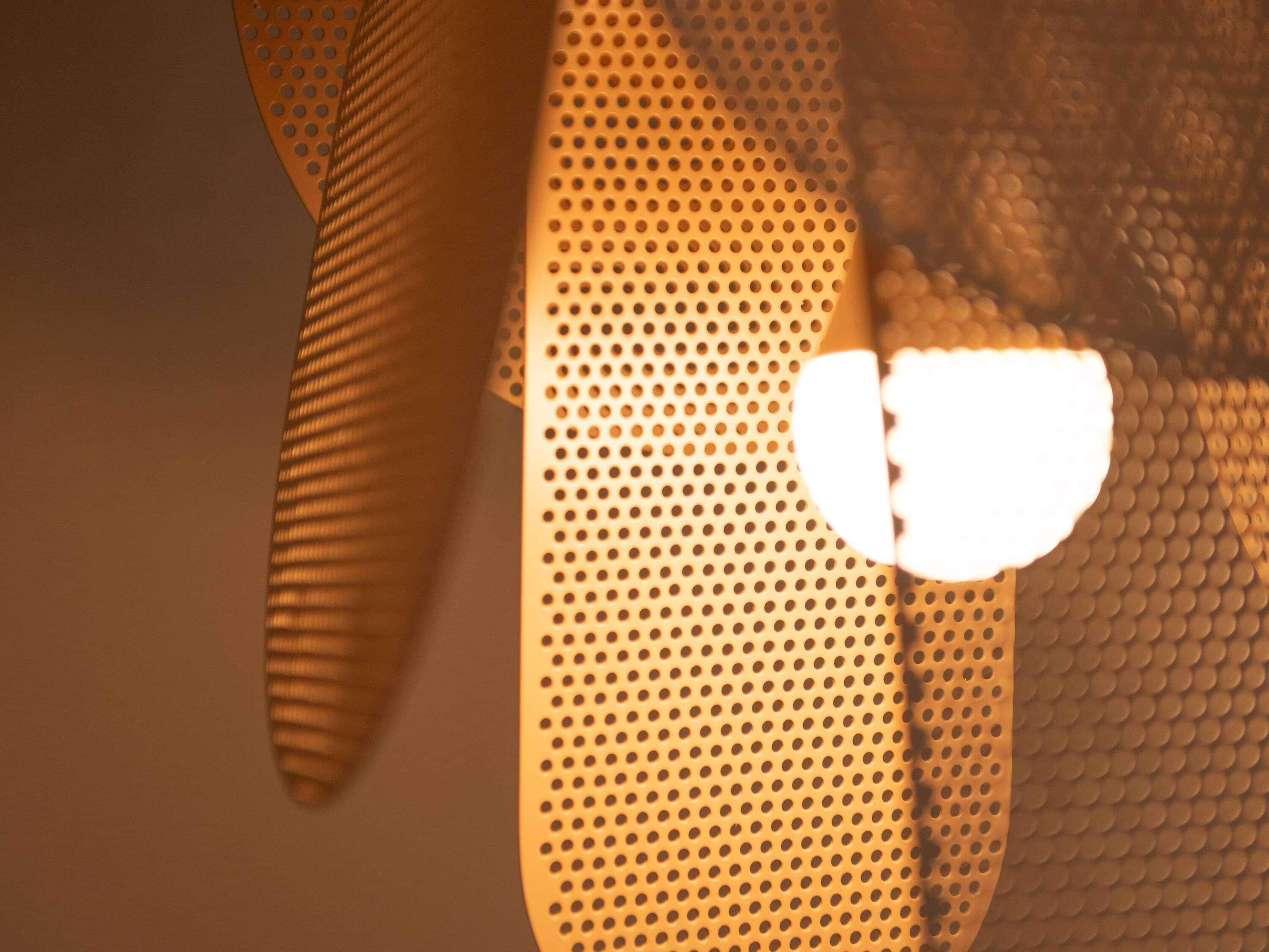 A close-up of a textured wall with a perforated pattern and a reflective surface.