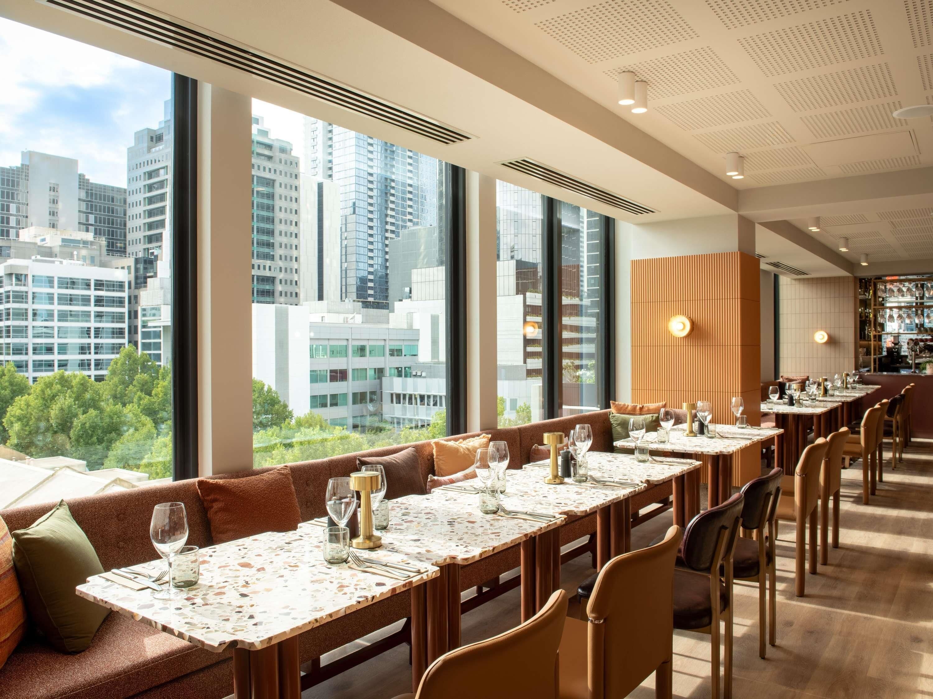Un comedor moderno con techos altos, ventanas amplias y vistas a la ciudad.