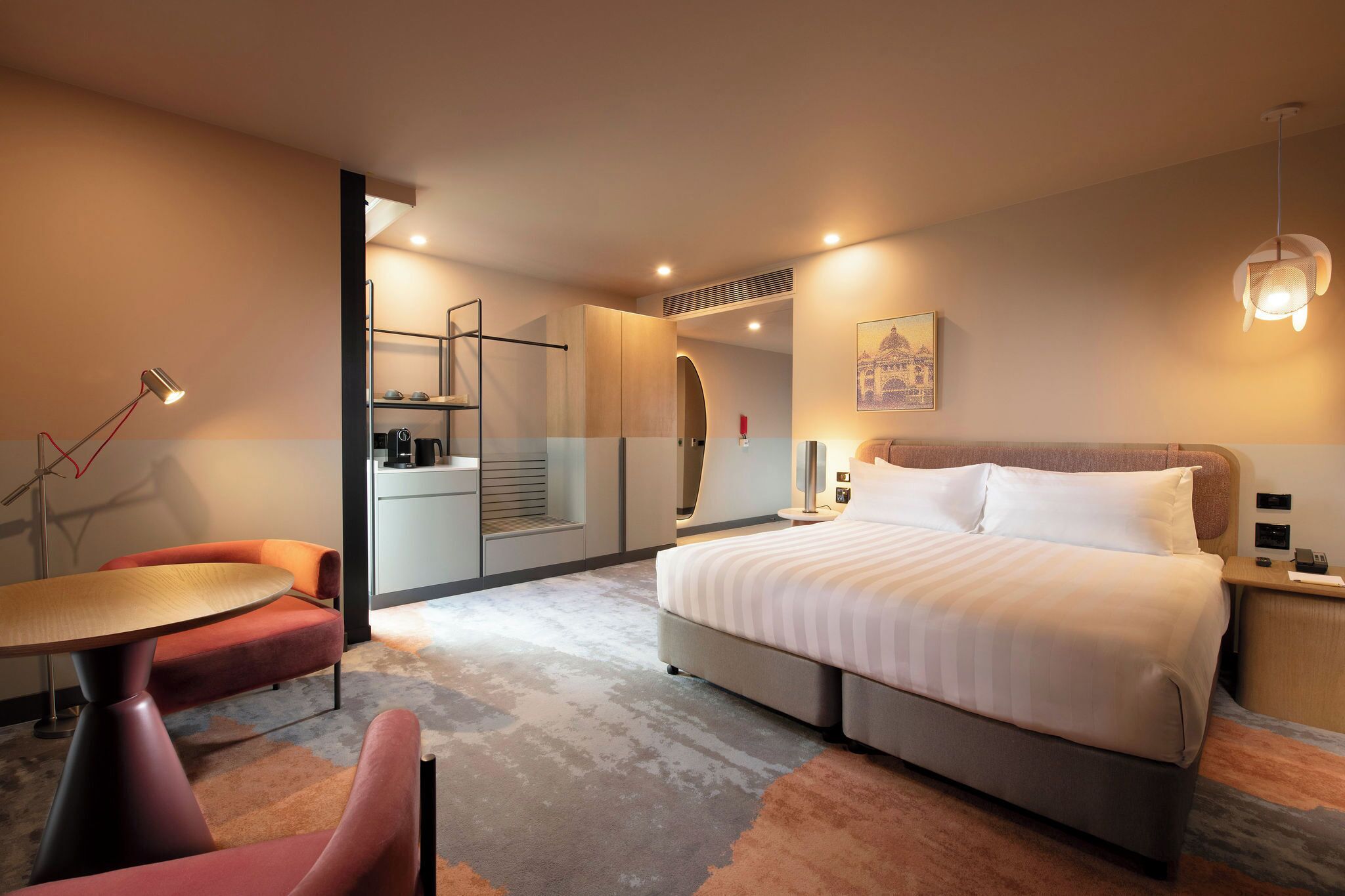 Una habitación de hotel moderna con cama, escritorio, silla y una mesita.