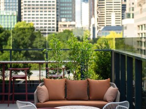 Un balcón con un sofá, una mesita y una silla.