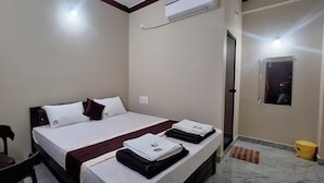 A hotel room with a bed, a chair, a desk, and a mirror. - Highway Heaven (Bhatkal)