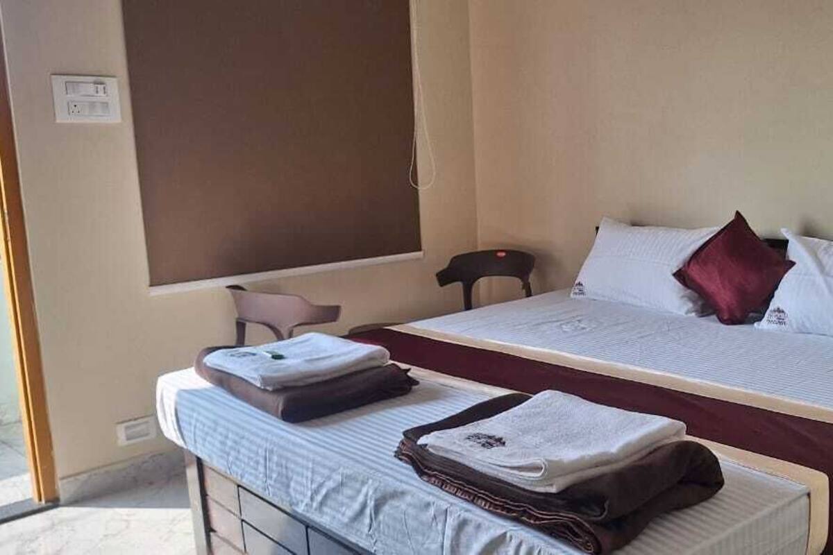 A hotel room with a bed, a desk with a chair, and a window.