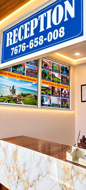 A reception desk with a blue sign indicating the reception area and a phone number. - Highway Heaven (Bhatkal)