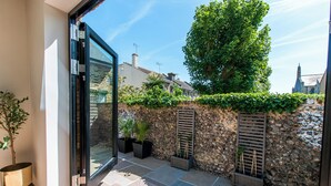 Une terrasse extérieure moderne avec un sol en pierre, des plantes en pot et un mur en pierre.