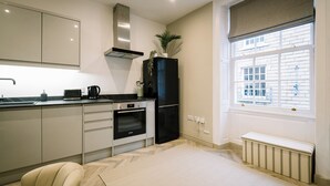 A modern kitchen with a built-in oven, a black refrigerator, and a window with a view of buildings. - Sun St Apartment 4 (Lancaster)