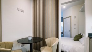 A bedroom with a bed, a bedside table, and two chairs. - Sun St Apartment 4 (Lancaster)