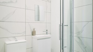 A modern bathroom with a toilet, sink, and glass-enclosed shower. - Sun St Apartment 4 (Lancaster)