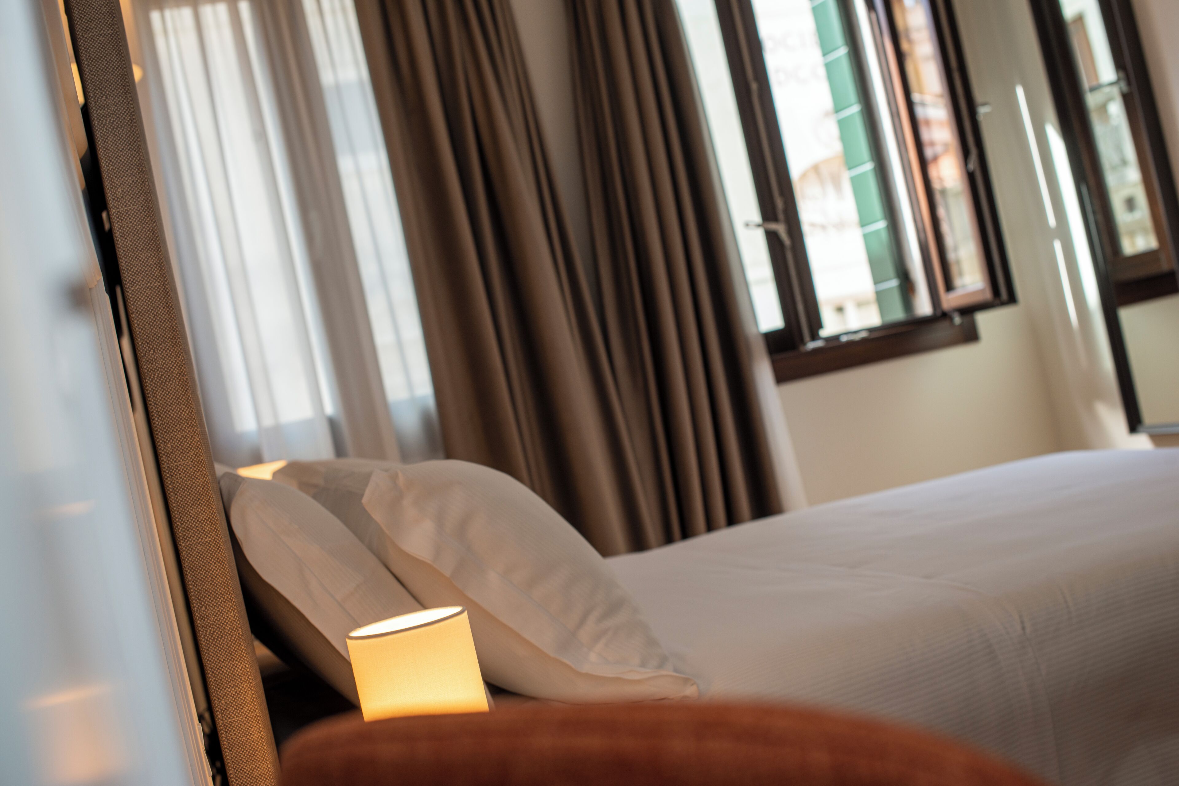 A hotel room with a bed, curtains, and a window with blinds.