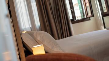 A hotel room with a bed, curtains, and a window with blinds.