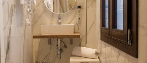 Une salle de bain avec un mur en marbre, un lavabo, des toilettes, un miroir et une fenêtre.