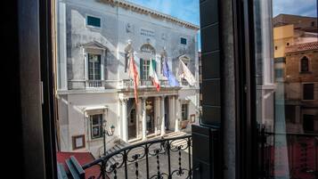 A building with classical architecture, featuring columns, a balcony, and flags.
