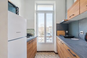 Eine moderne Küche mit einem Kühlschrank, Holzschränken, einem Fenster und einer Arbeitsfläche mit einem Wasserkocher.