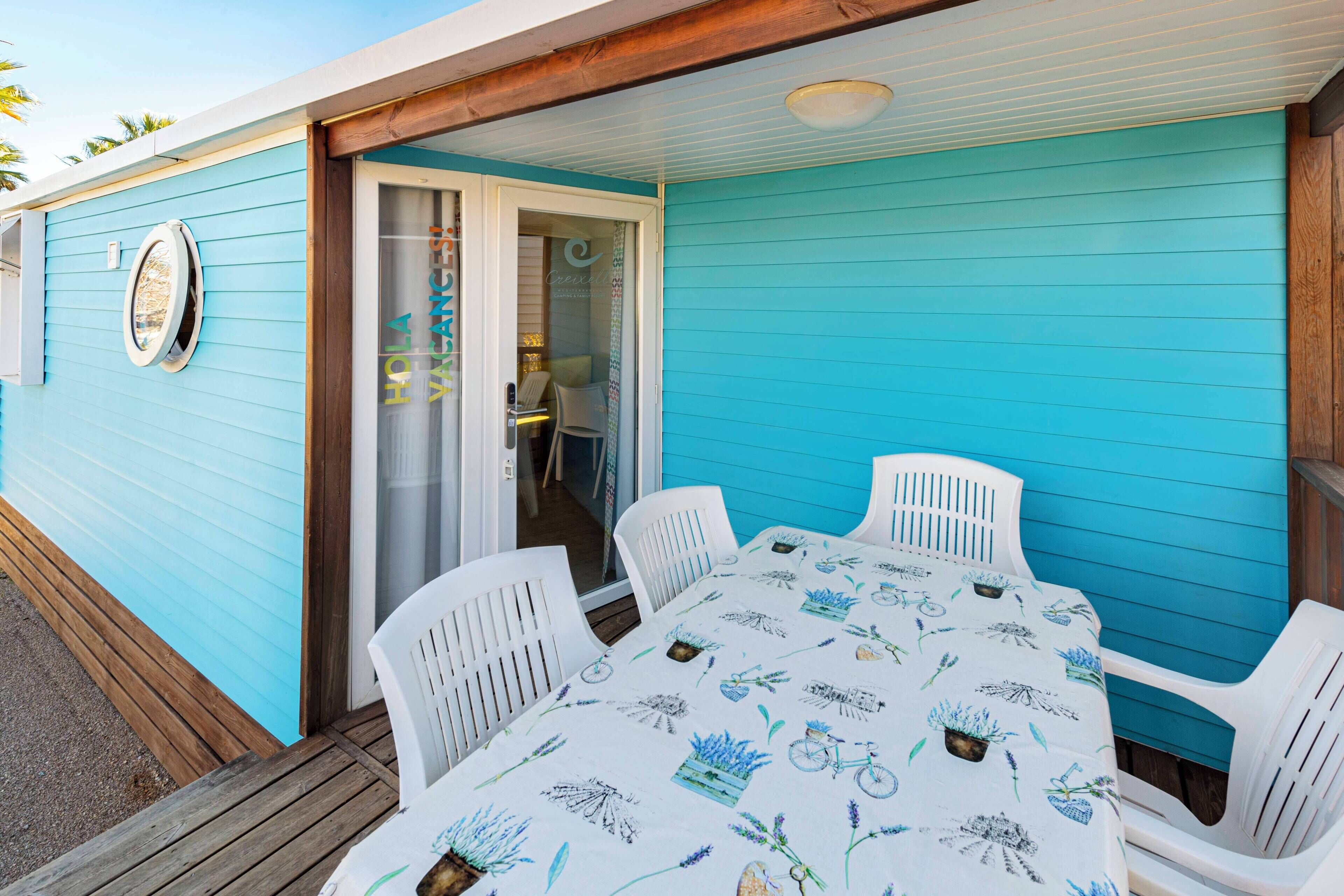 A covered patio with a table and chairs, a sliding glass door, and a blue exterior wall.